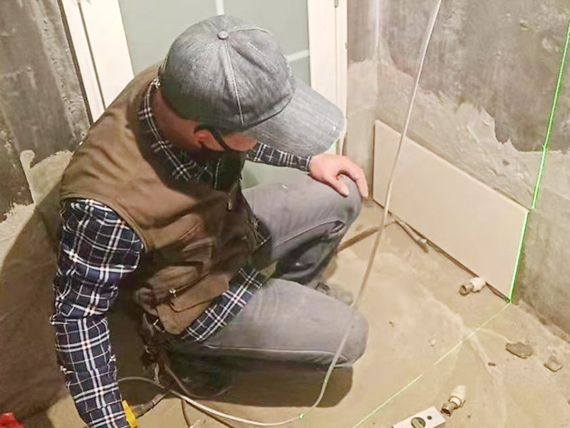衛生間墻面貼磚：施工前將需要的材料整齊堆放在一旁待用。首先應除去基層表面的污垢，油漬，浮灰;除去基層上所有涂料層，膩子層;如果基層未能達到平整度要求，需對基層進行預先的找平處理。 鋪貼瓷磚前需事先找好垂直線，以此為基準鋪貼的瓷磚高低均勻、垂直美觀;此外，施工前在墻體四周需彈出標高控制線，在地面彈出十字線，以控制地磚分隔尺寸。 加水后將粘結劑漿料攪拌至潤滑均勻，無明顯塊狀或糊狀結塊，攪拌后的漿料靜置5-10分鐘后再稍加攪拌1-2分鐘即可使用。在開始鋪貼施工前，需要先清理瓷磚表面的浮灰，污垢等。將調制好的漿料均勻地抹在瓷磚背面，要求漿料飽滿。將瓷磚平整地鋪貼在基層上，使用橡膠錘將瓷磚拍實鋪平。施工過程中，可小幅度轉動瓷磚，使漿料與瓷磚背面充分接觸。